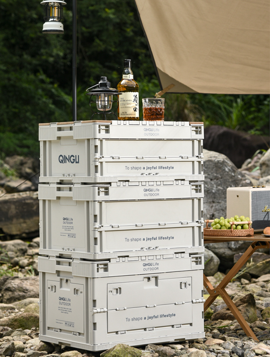 Three stacked Setstead 65L Multifunction Storage Boxes beside a campsite table and lantern