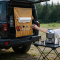 Setstead Hanging Camp Organizer hanging from an SUV tailgate with paper towels, utensils, and a camp stove nearby